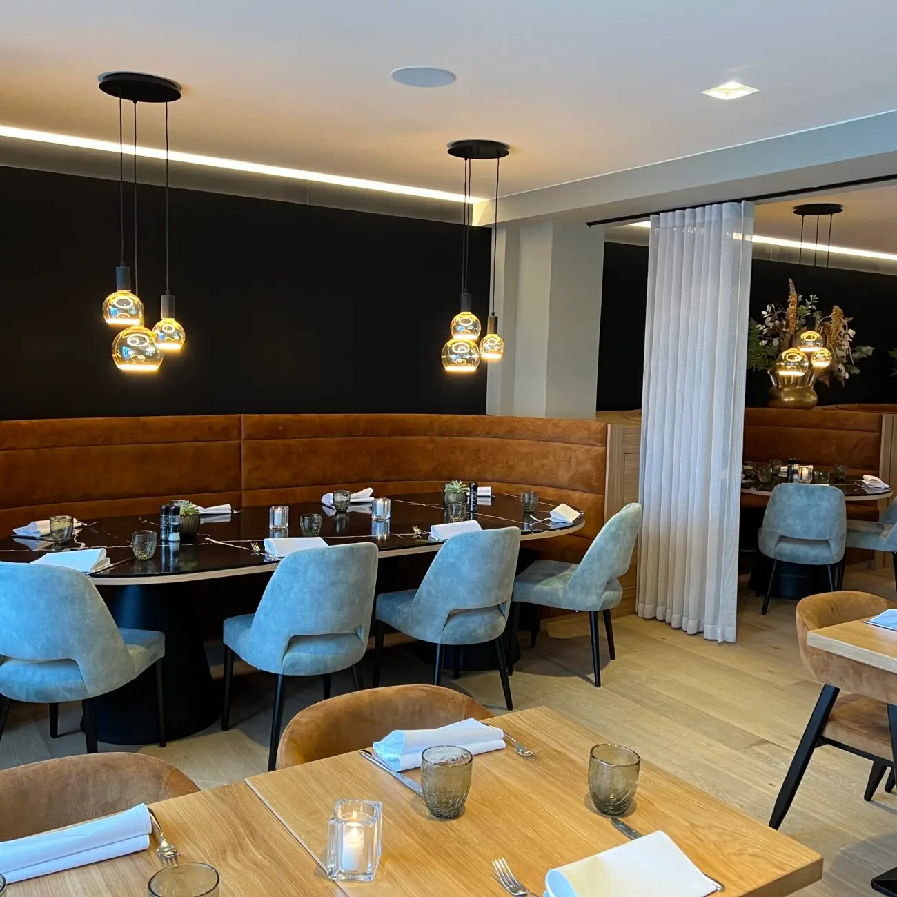 Ronde zitbank met marmeren tafel en gouden hanglampen in het vernieuwde interieur